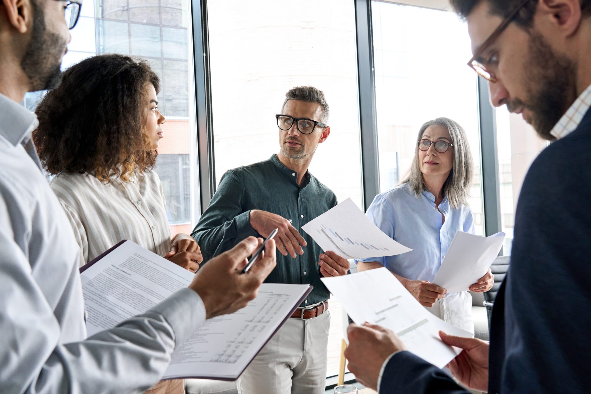 Multiethnic business executive team having discussion at office meeting. Diverse multiracial corporate leaders group brainstorming analyzing project financial result in board room developing strategy.